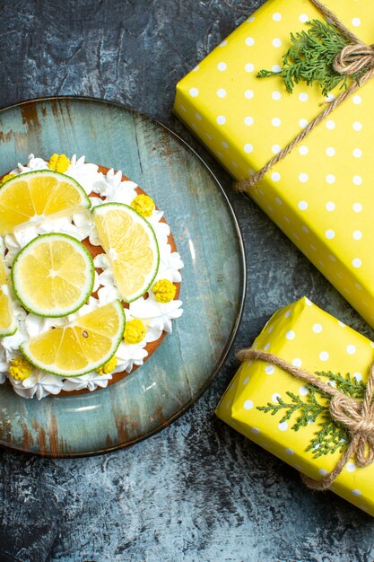 Pionowy widok świątecznych żółtych pudełek na prezenty i ciasta ozdobionych cytrynowymi limonkami na ciemnym tle