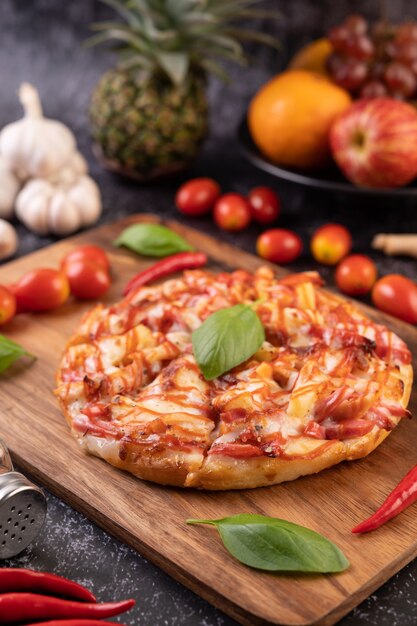 Pizza na drewnianej tacy z pomidorami Chili i bazylią.