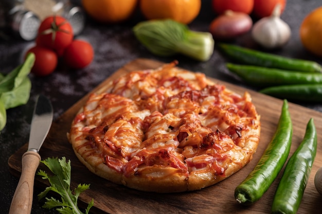Bezpłatne zdjęcie pizza z kiełbasą, kukurydzą, fasolą, krewetkami i boczkiem na drewnianym talerzu