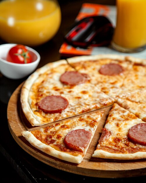 Pizza z pokrojonymi kiełbaskami i sokiem pomarańczowym