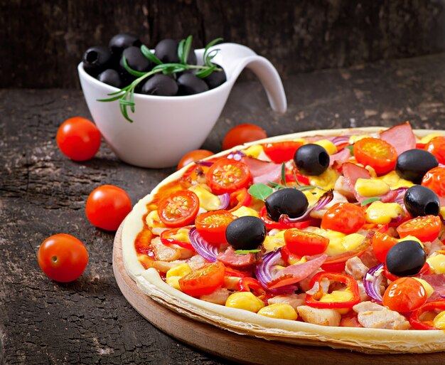 Pizza z warzywami, kurczakiem, baleronem i oliwkami odizolowywającymi na bielu