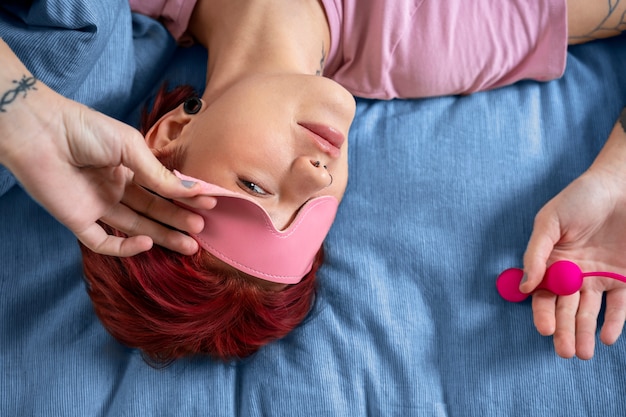 Płaska kobieta leżąca w łóżku z zabawką erotyczną