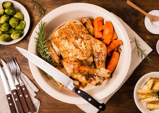 Płaski talerz z pieczonym kurczakiem w Święto Dziękczynienia i innymi potrawami