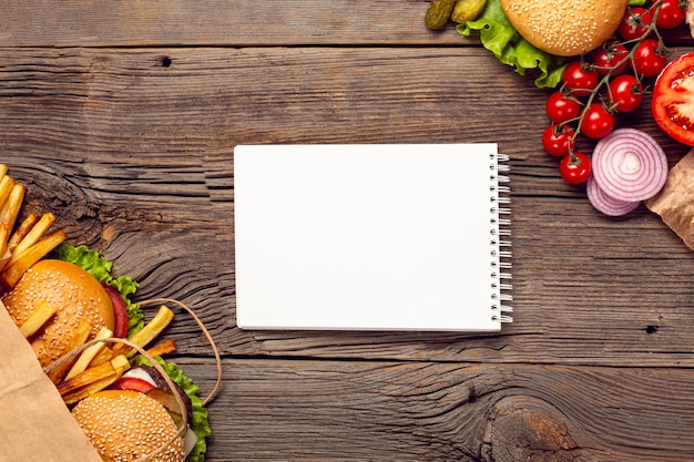 Bezpłatne zdjęcie płaskie leżące hamburgery z makietą notatnika