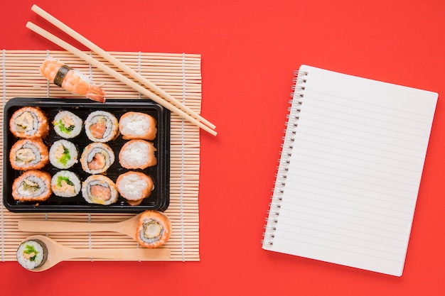 Bezpłatne zdjęcie płaskie świeża kompozycja sushi z szablonu notatnika