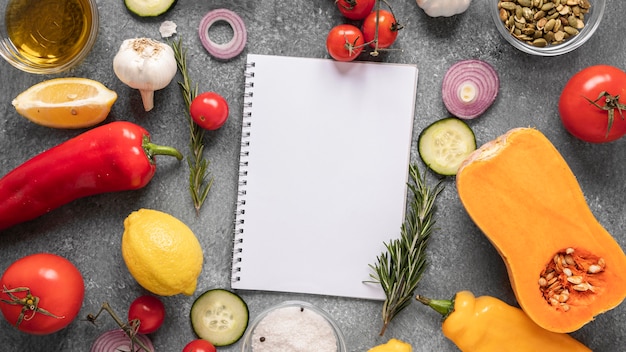 Płaskie układanie składników żywności z notatnikiem i warzywami