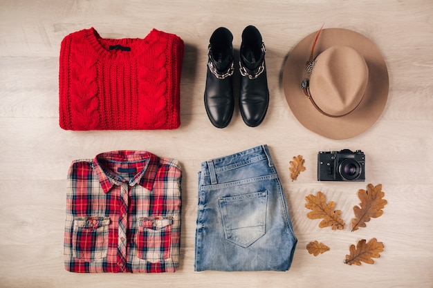 Płaskie ukształtowanie kobiecego stylu i akcesoriów, czerwony sweter z dzianiny, koszula w kratę, dżinsy, czarne skórzane buty, czapka, jesienny trend w modzie, widok z góry, aparat fotograficzny w stylu vintage, strój podróżnika