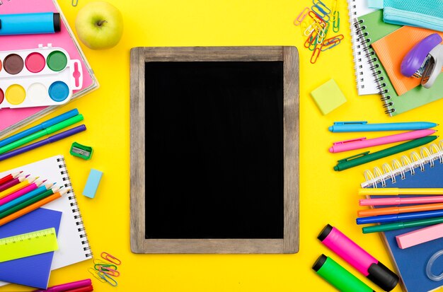 Płaskie ukształtowanie przyborów szkolnych z tablicą i kolorowymi ołówkami
