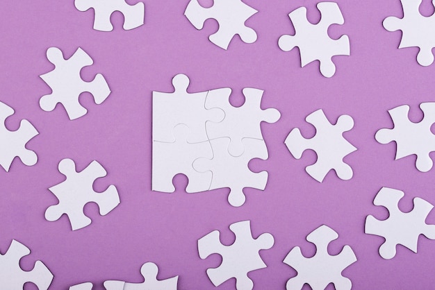 Płaskie ułożone białe puzzle i fioletowe tło