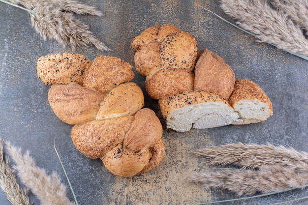 Plasterki bochenka chleba strucia i wiązka łodyg pszenicy na marmurowej powierzchni