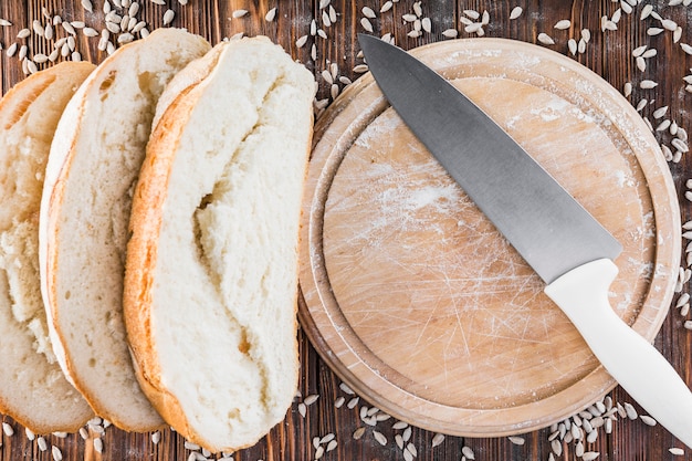 Plasterki chleb i słonecznikowi ziarna na drewnianej ciapanie desce z nożem