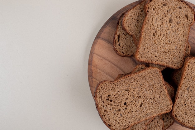 Plasterki ciemnego chleba na drewnianym talerzu. Wysokiej jakości zdjęcie