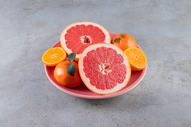 Plasterki owoców cytrusowych pomarańczy i grejpfruta ułożone na talerzu.