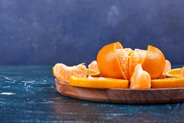 Plasterki pomarańczy i mandarynek na drewnianym talerzu
