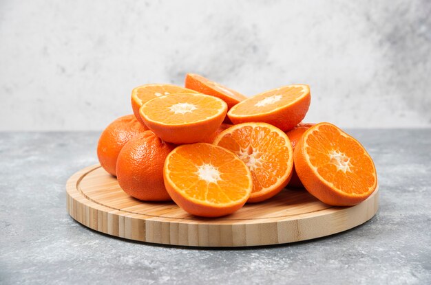 Plasterki soczyste, świeże, pomarańczowe owoce w drewnianej tablicy.