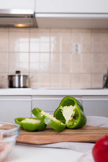 Plasterki zielony dzwonkowy pieprz na ciapanie desce w kuchni