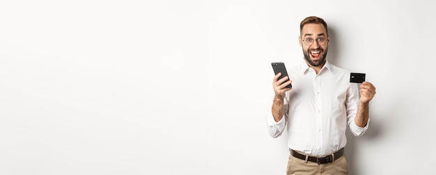 Płatności Biznesowe I Internetowe Podekscytowany Mężczyzna Płacący Telefonem Komórkowym I Kartą Kredytową Uśmiechnięty Zdumiony Stan