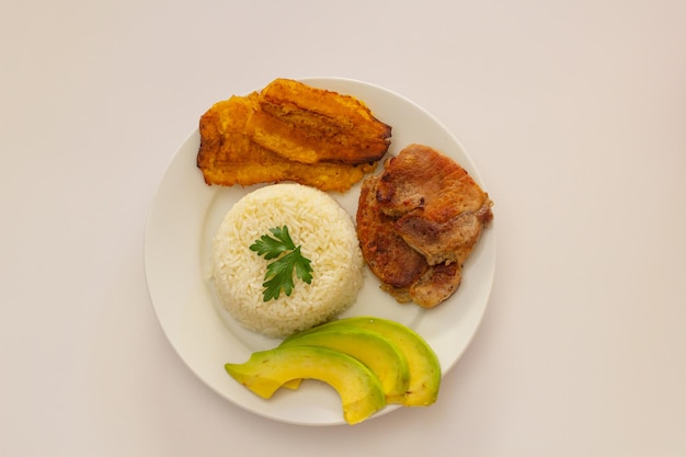 Plato almuerzo dominicano, tostones fritos, arroz blanco acompañados de varios aguacates cortados, comida en casa, toma superior