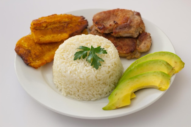 Plato almuerzo dominicano, tostones fritos, arroz blanco acompañados de varios aguacates cortados, comida en casa,