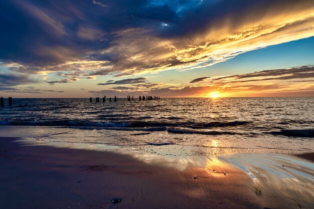 Plaża otoczona morzem z pionowymi drewnianymi deskami podczas zachodu słońca wieczorem