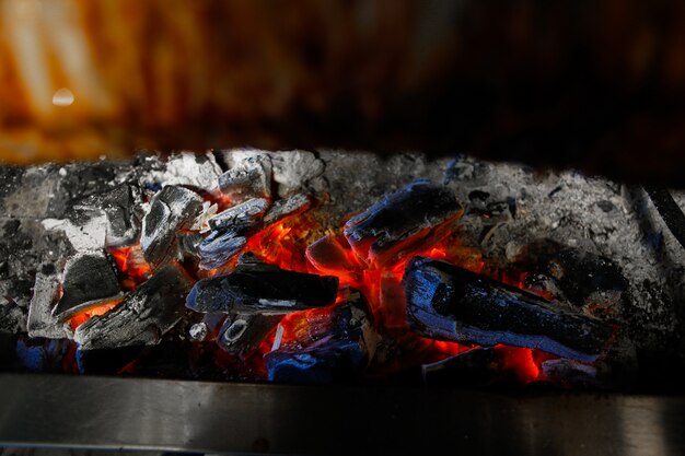 Płonące węgle drzewne pod widokiem z boku pieca do smażenia mięsa