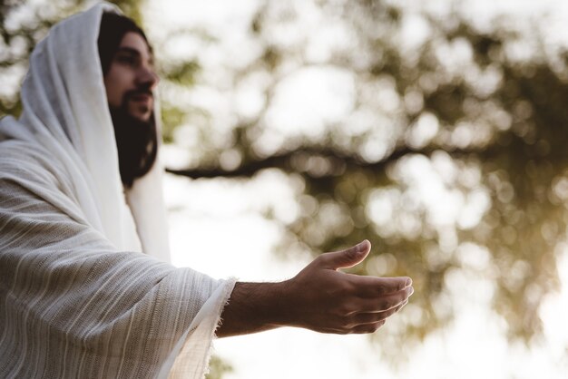 Płytkie ujęcie przedstawiające Jezusa Chrystusa wyciągającego pomocną dłoń