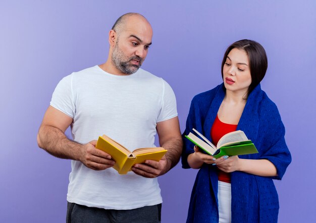 Pod wrażeniem dorosłej kobiety para owinięta w szal zarówno trzymając książkę, jak i patrząc na swoje książki