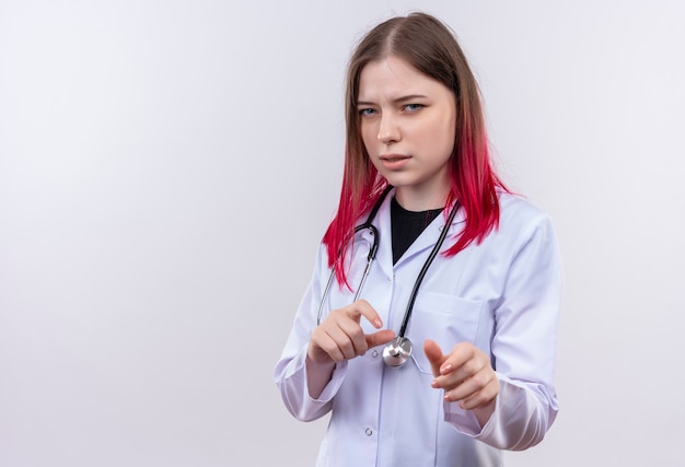 Pod wrażeniem młoda kobieta lekarz noszenie stetoskop medycznej szaty, trzymając się za ręce wokół żołądka na odosobnionej białej ścianie z miejsca na kopię