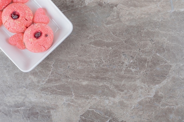 Bezpłatne zdjęcie podawanie różowych ciasteczek i galaretkowych cukierków na półmisku na marmurowej powierzchni