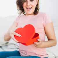 Bezpłatne zdjęcie podekscytowana kobieta otwiera pudełko w kształcie serca