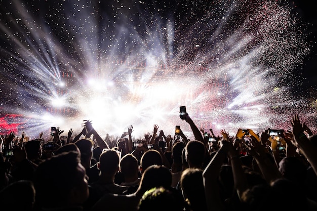 Podekscytowana publiczność oglądająca konfetti fajerwerków i bawiąca się nocą na festiwalu muzycznym