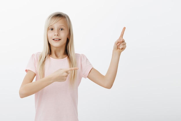 Bezpłatne zdjęcie podekscytowane dziecko wskazujące palcami w prawym górnym rogu