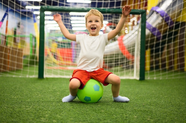 Podekscytowany chłopiec siedzi na piłkę