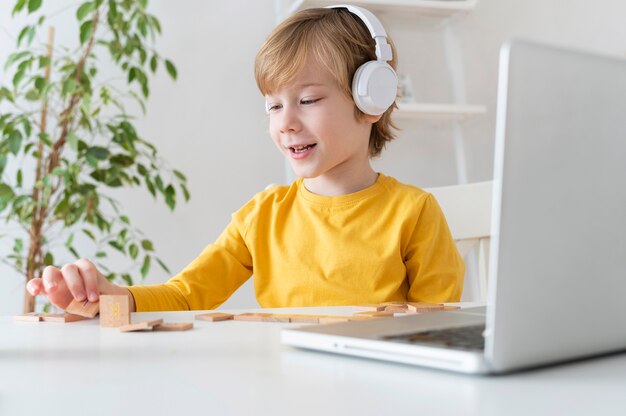 Podekscytowany chłopiec za pomocą laptopa i słuchawek w domu