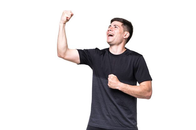 Podekscytowany mężczyzna fitness z gestem zwycięzcy na białej ścianie
