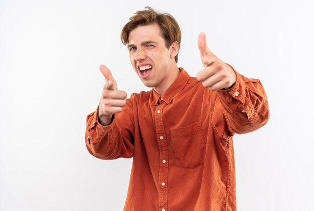 Podekscytowany młody przystojny facet ubrany w czerwoną koszulę pokazując kciuk do góry na białym tle na białej ścianie