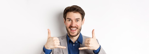 Bezpłatne zdjęcie podekscytowany sprzedawca uśmiecha się, pokazując znaki telefoniczne i prosząc o telefon, podając swój numer