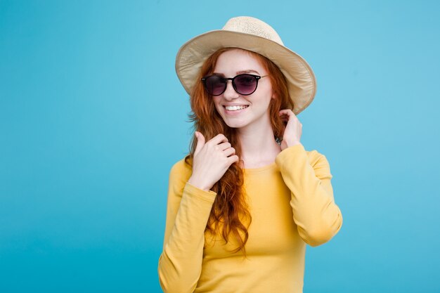 PodrÃ³Å¼e koncepcji - Zamknij w górę Portret młodych piękne atrakcyjne redhair girl wtih modne kapelusz i okulary uśmiecha się. Niebieskie Tło Pastelowe. Skopiuj miejsce.