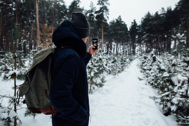 Podróżnik bierze selfie śnieżny krajobraz w zima lesie na telefonie komórkowym