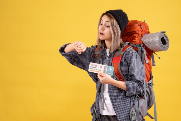 podróżująca kobieta z plecakiem trzymająca bilet sprawdzający czas