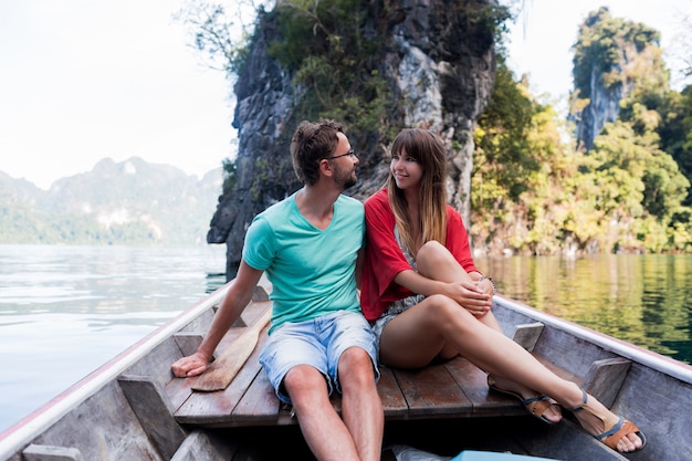 Podróżująca para zakochanych przytulająca się i relaksująca na łodzi longtail w lagunie na tajskiej wyspie. Ładna kobieta i jej przystojny mężczyzna spędzają razem wakacje. Wesoły nastrój. Czas przygody.