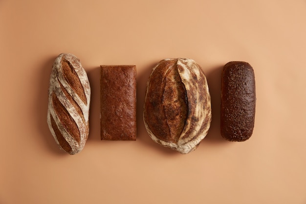 Bezpłatne zdjęcie podstawowe pojęcia żywności i zdrowego odżywiania. cztery rodzaje chleba na białym tle na brązowym tle. chleb pszenny, żytni, orkiszowy wzbogacony witaminami i minerałami z organicznej mąki ma właściwości prozdrowotne