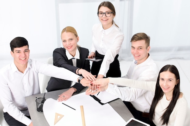Bezpłatne zdjęcie podwyższony widok biznesmen i businesswoman układania nawzajem ręce nad projektem