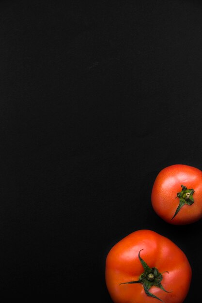 Podwyższony widok dwa czerwonego pomidoru na czarnym tle