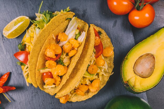 Podwyższony widok meksykańskie tacos kukurydzy z warzywami i awokado na czarnym łupku