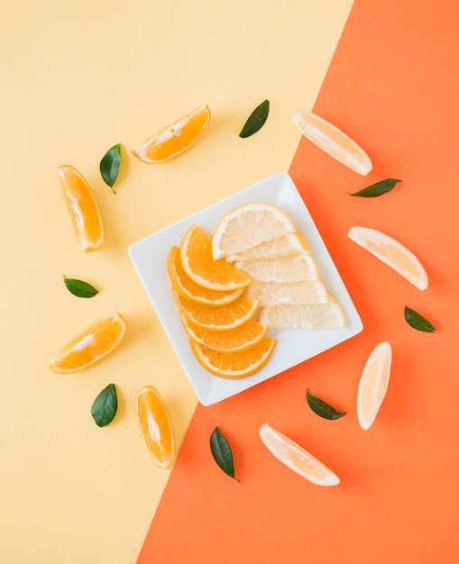 Bezpłatne zdjęcie podwyższony widok plasterki pomarańczy i cytryny na talerzu nad podwójnym tłem