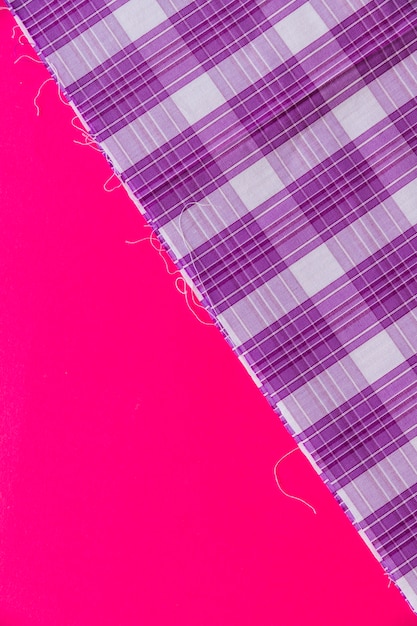 Bezpłatne zdjęcie podwyższony widok purpurowy w kratkę deseniowa tkanina na różowym tle