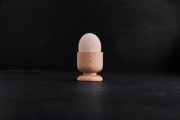 Pojedyncze jajko w małej drewnianej filiżance.