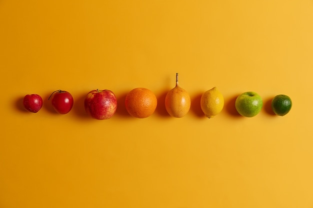 Pojedyncze owoce cytrusowe w rzędzie na żółtym tle. Zielona limonka, jabłko, cytryna, kumkwat, pomarańcza, fortunella i brzoskwinia. Pożywne owoce tropikalne z mnóstwem witamin, które pomogą Ci zachować zdrowie