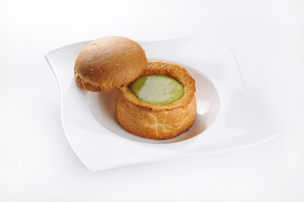 Pojedyncze ujęcie białej płytki z ciasta z zielonym sosem - idealne do wykorzystania w blogu kulinarnym lub w menu